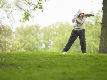 Young man wearing hooded sweatshirt practicing boxing in park