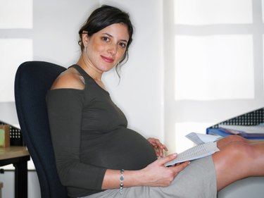 Pregnant young woman with paperwork, portrait