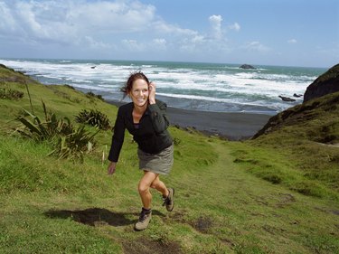 Woman walking up hill, beach in background