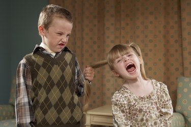 Boy (6-7) pulling girl's (4-5) hair in room