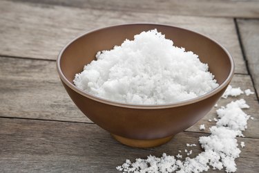 Sea salt in bowl on wooden table
