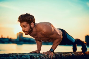 Picture of a young athletic man doing push ups outdoors.