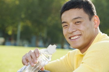 Young Athletic Man Sitting on the Grass in a Park, Close Up