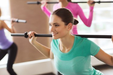 group of people exercising with bars in gym