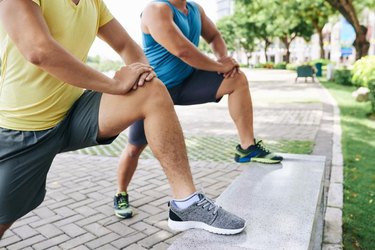Cropped image of sporty people doing lunges in city park