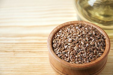 Flax seeds in  wooden bowl , linseed oil on  wooden background