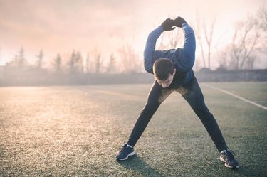 Handsome athlete warming up before jogging