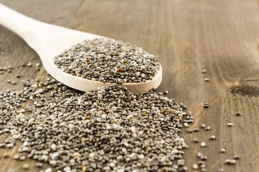Chia seeds on wooden spoon and vintage wooden background