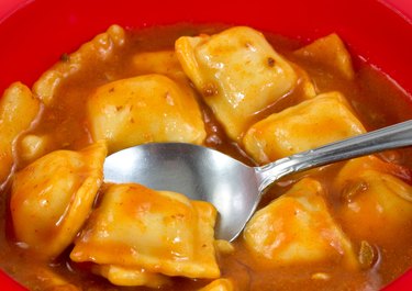 Ravioli in a red bowl with a spoon