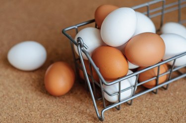 White and brown eggs in metal basket close up