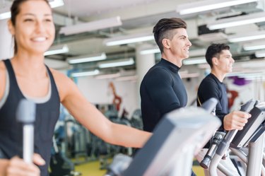 Man and beautiful woman using a stepper in a gym