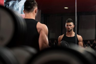 Man In The Gym Exercising Biceps With Dumbbells