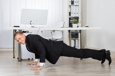 Young Businessman Doing Pushup At Work In Office