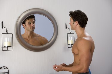 Muscular man looking at reflection in mirror