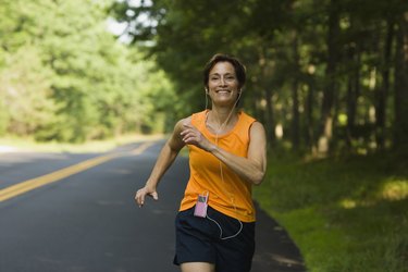 Smiling woman jogging along road