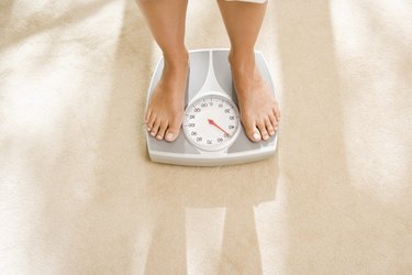 overhead photo of feet on a scale on tan marble floor