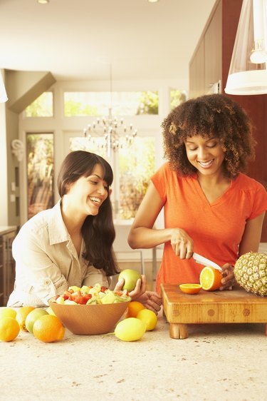 Multi-ethnic female friends cutting fruit