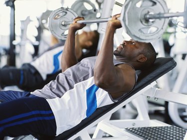 Two mid adult men exercising in a gym with weights