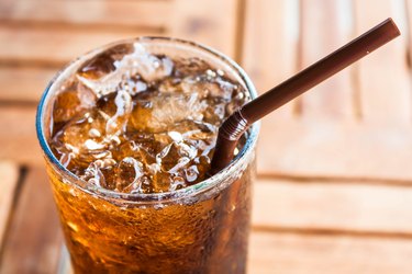 glass of dark soda with a straw sticking out of it