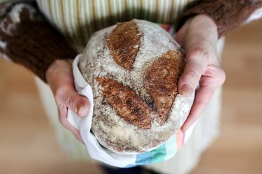 Whole-grain artisan bread loaf in grandmother hands, baking