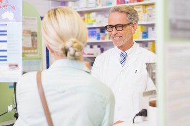 Senior pharmacist speaking with customer