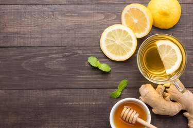 Cup of ginger tea with lemon and honey on table.