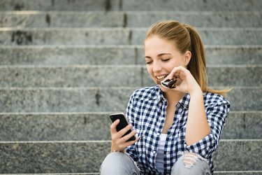 Teenager eating chcolate looking in phone