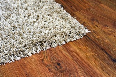 Parquet floor of the brown wooden planks and white shaggy carpet