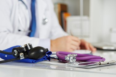 Stethoscope head lying on medical forms on clipboards closeup