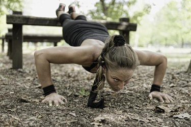 Female athlete doing push ups on fitness trail in park