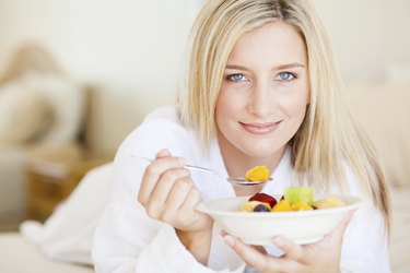 young woman eating breakfast in bed