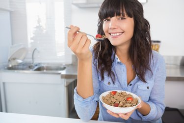 Attractive brunette eating bowl of cereal and fruit