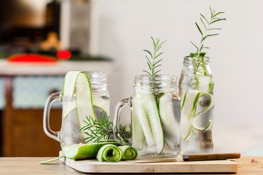 glass jars of cucumber and rosemary on wooden table
