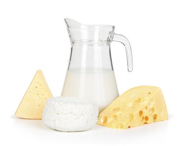 Cheeses next to a pitcher of milk, to represent dairy products with lactose