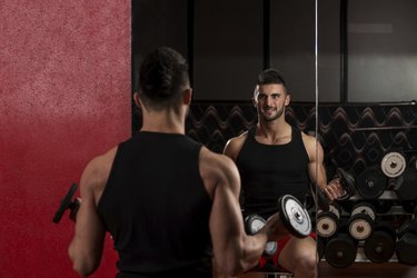 Young Man Lifting Dumbbell In Gym