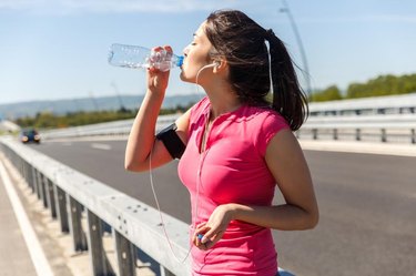 Young woman taking a break from exercising, She is drinking water
