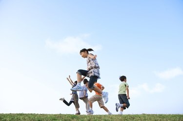School children jumping at riverbank, copy space