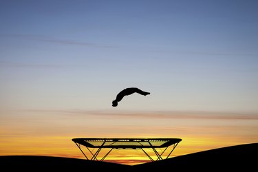 silhouetted gymnast on trampoline at sunset