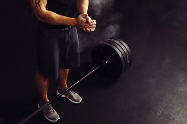 Athlete clapping hands with talc before deadlift barbells workout