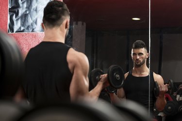 Young Man Lifting Dumbbell In Gym