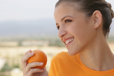 Young woman smiling with orange in her hand