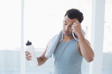 Man wiping sweat with towel in fitness studio