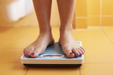 Close-up of woman's feet standing on scale in the bathroom