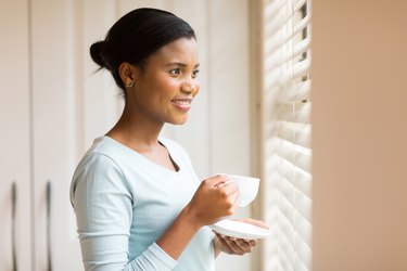 african woman drinking coffee near the window