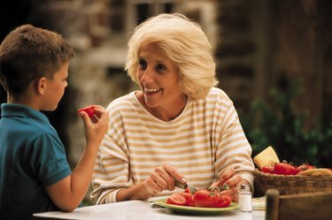 Grandmother with grandson while cutting tomatoes