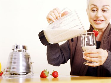 Senior woman pouring fruit smoothie