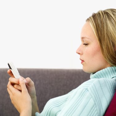 Young woman sitting on a couch operating a mobile phone