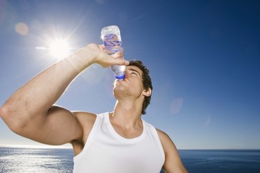 Man drinking bottle of water outdoors after workout