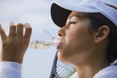 Hispanic woman drinking from water bottle