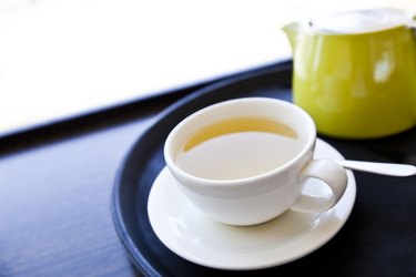 Cup of Green Tea on a tray with saucer and spoon